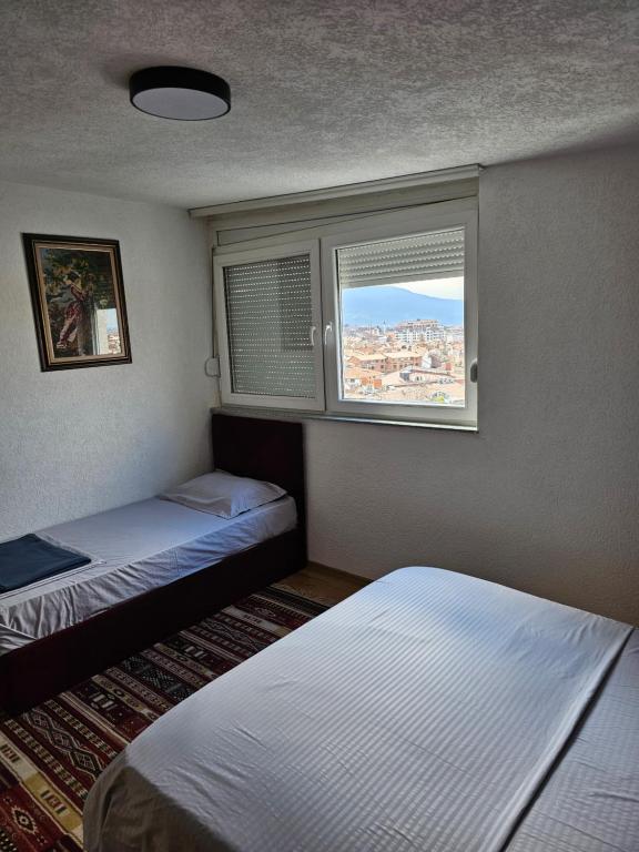 普里兹伦Skyland Apartment Prizren的小房间设有两张床和窗户