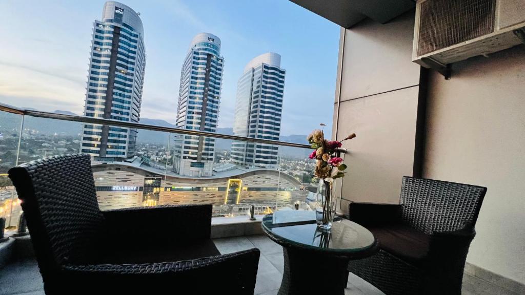伊斯兰堡Sky Heights Executive Apartments Facing Centaurus Mall Islamabad的阳台配有桌椅,享有高楼的景致。