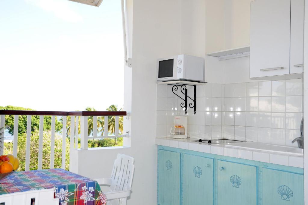 勒穆莱Résidence Tropicale的厨房配有蓝色橱柜、桌子和窗户。