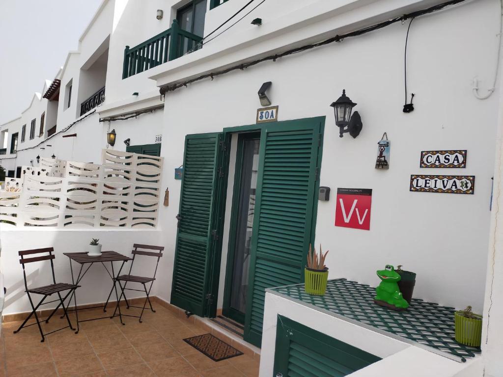 蓬塔穆赫雷斯Casa Leiva的一个带绿门和桌椅的庭院