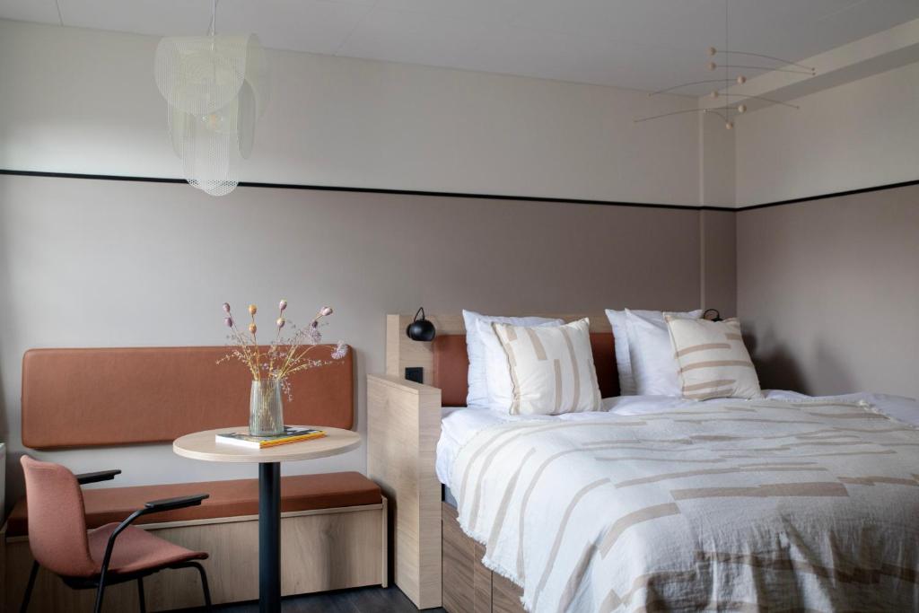 哥本哈根Bob W Østerbro Copenhagen的卧室配有1张床、1张桌子和1把椅子