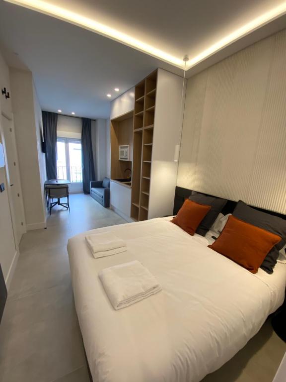 索里亚Apartamentos "El collado Suites" Soria Centro的卧室配有带橙色枕头的大型白色床