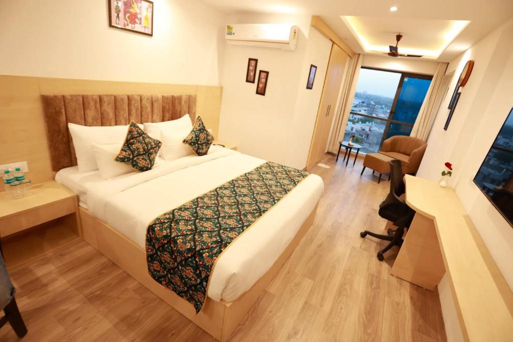 斋浦尔Diona Anukampa Suite Room with rooftop pool的配有一张床、一张书桌和一扇窗户的酒店客房
