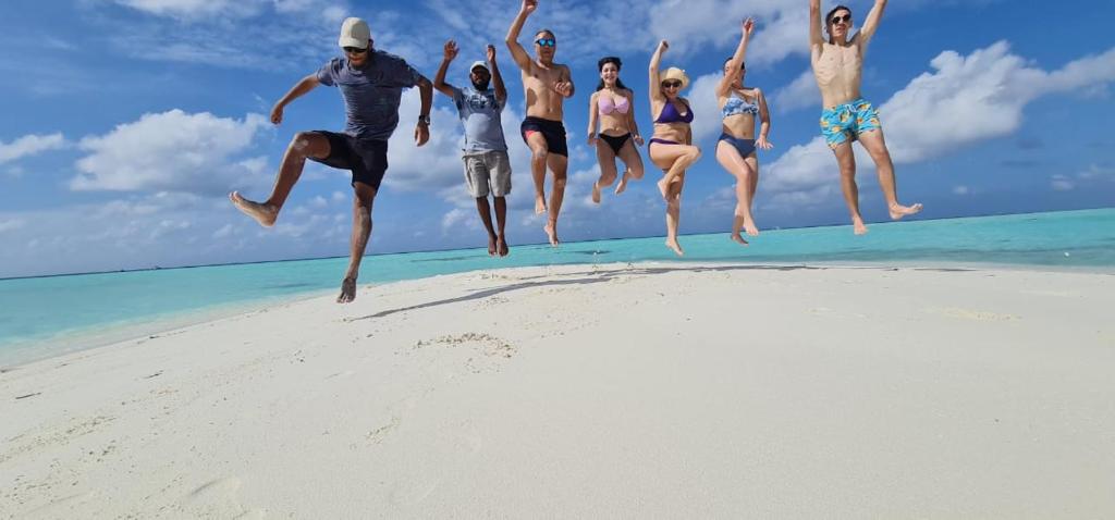 MahibadhooLiberty Guesthouse Maldives的一群人跳上海滩的空中