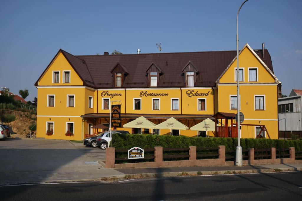 弗兰季谢克矿泉镇Penzion Eduard的一座黄色的大建筑,前面有一辆汽车