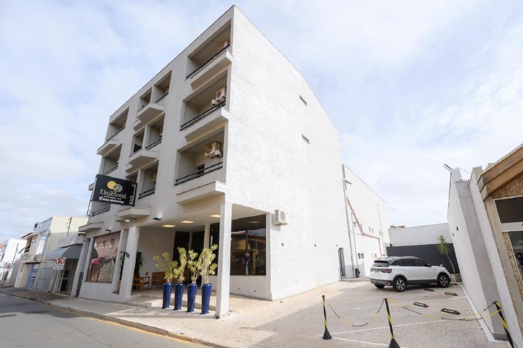 伊塔佩蒂宁加Universitario Hotel的前面有一辆汽车停放的白色建筑