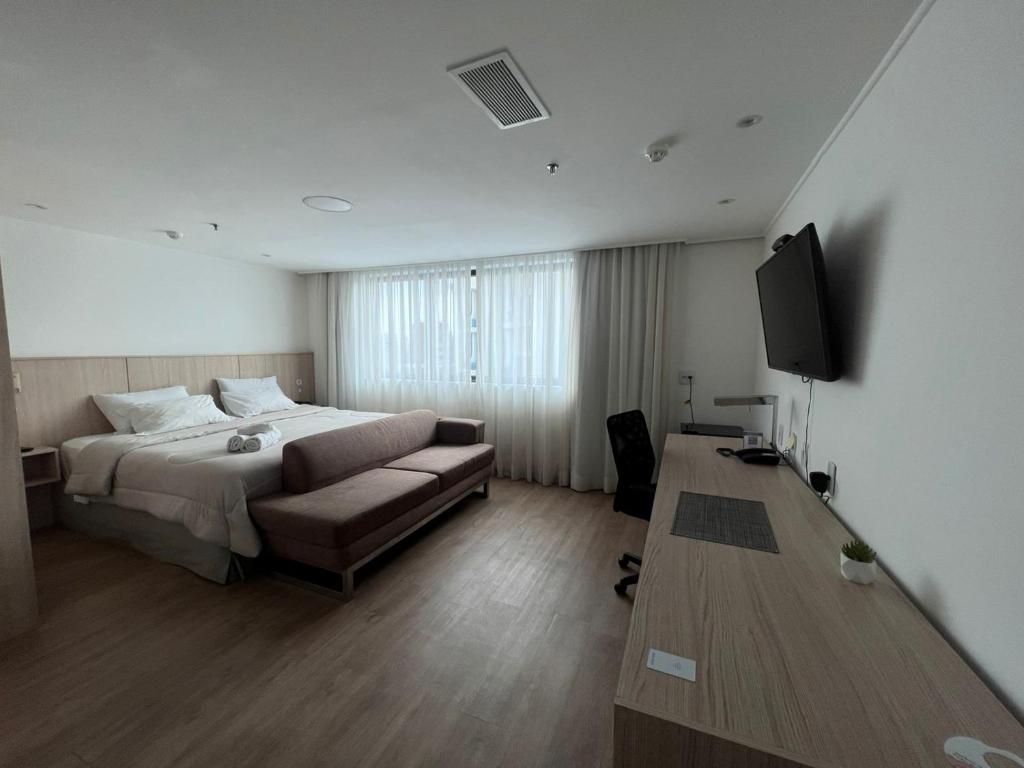 圣保罗Suíte 5 estrelas Hotel Av Ibirapuera 2534 Moema - 1的一间卧室配有一张床、一张沙发和一台电视
