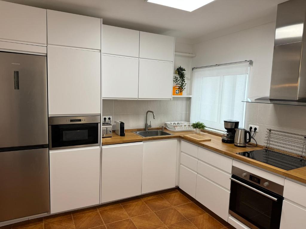 奥德米拉Cabo Sardão Guest House的厨房配有白色橱柜和不锈钢用具