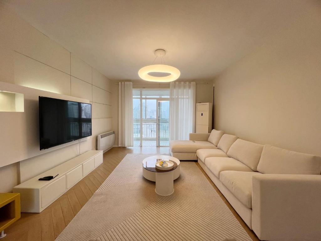 上海Shanghai Jing'an Temple Designer Boutique Large Four Rooms Apartment的客厅配有白色沙发和平面电视。