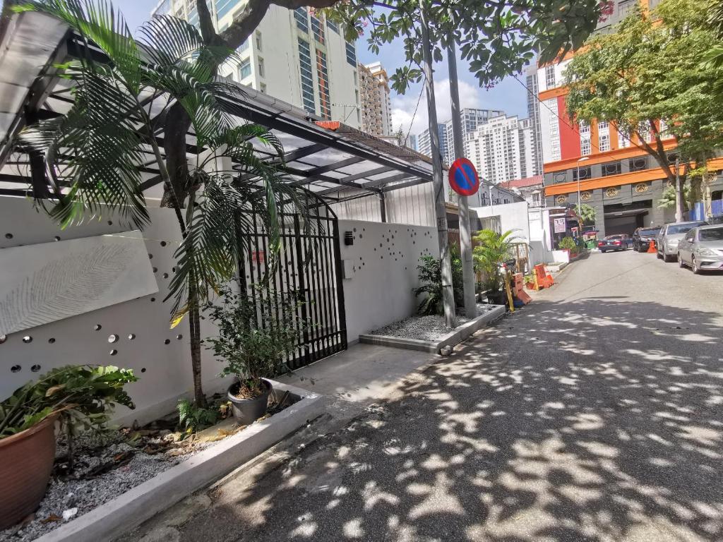 吉隆坡Autumn Guesthouse's near Jalan Alor Bukit Bintang的一条有栅栏、树木和建筑的街道