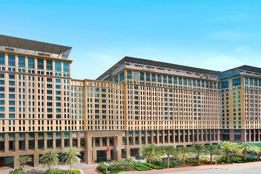迪拜Ritz Carlton DIFC Downtown Dubai的一座黄色的大建筑,前面有棕榈树