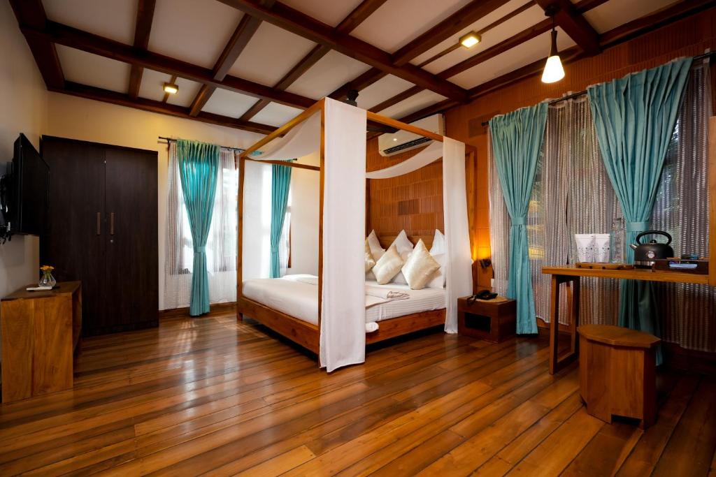 库玛拉孔Little Chembaka的一间卧室配有一张带蓝色窗帘的天蓬床