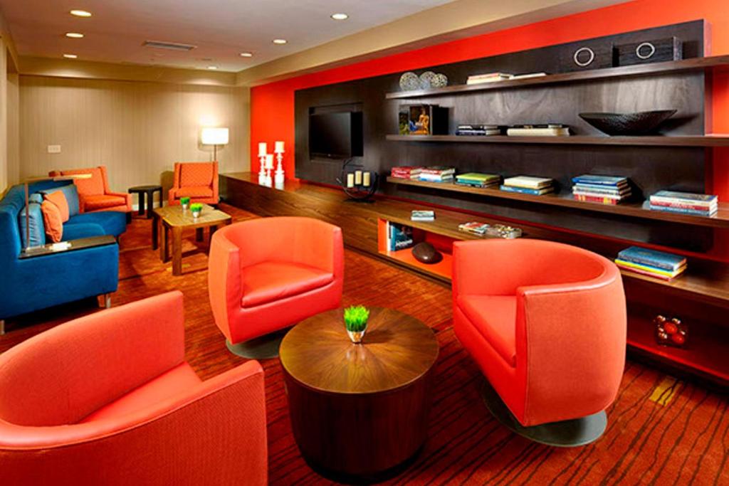Stow阿克伦斯托万怡酒店的客厅配有橙色椅子和电视