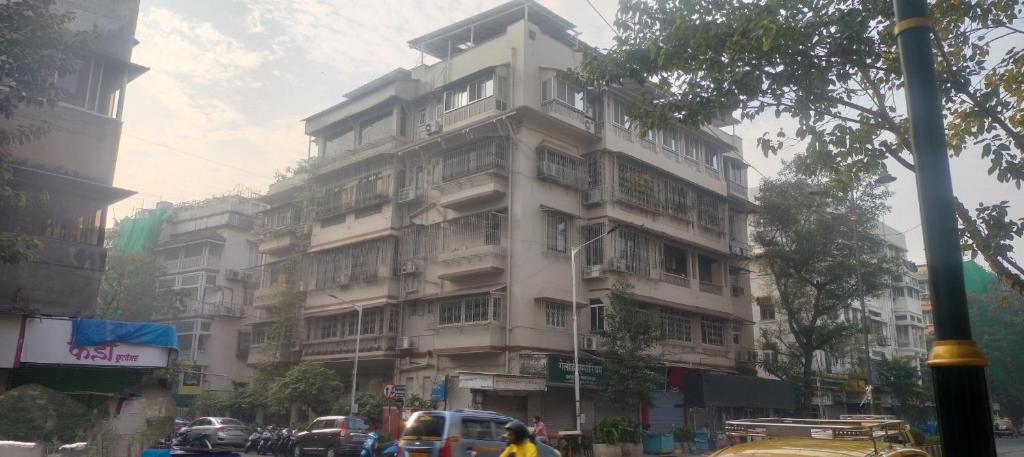 孟买戈拉巴住宿加早餐旅馆的城市街道上一座高大的白色建筑,交通繁忙