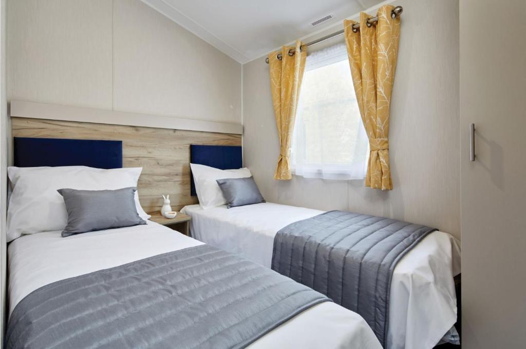 Burgh le MarshHome Farm Park - Static Caravans的一间卧室设有两张床和窗户。