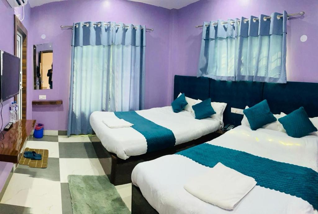 拜拉哈瓦Hotel Mangalam的紫色墙壁和蓝色窗帘的客房内的两张床