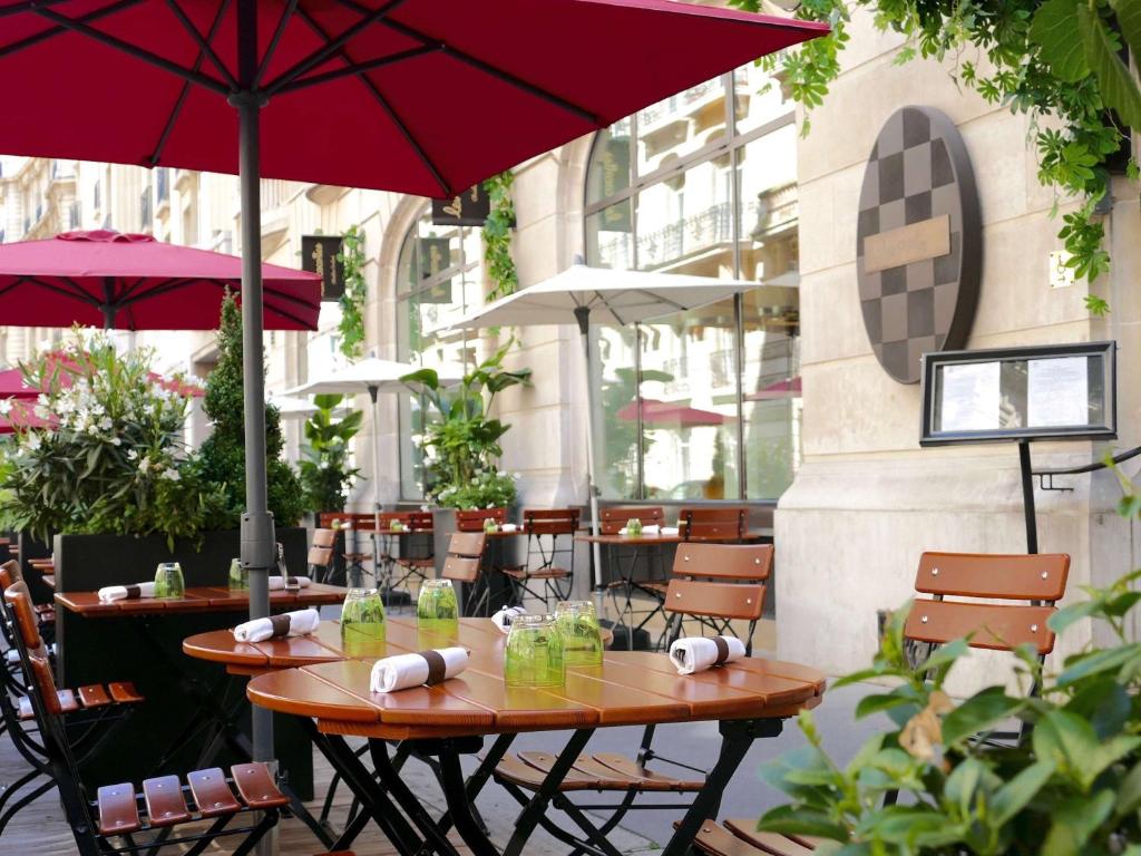 巴黎索菲特巴黎凯旋门酒店的庭院设有两张桌子和一把伞