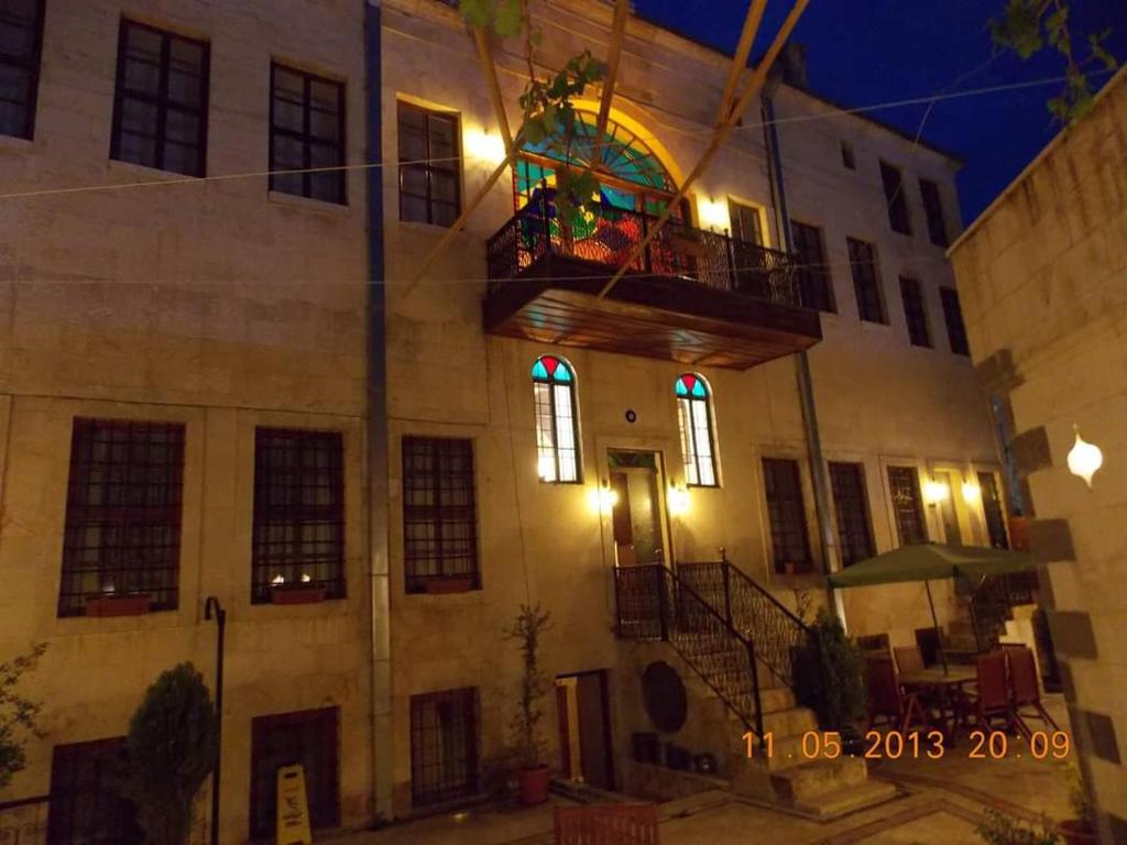 加济安泰普Hıdıroğlu Konağı Butik Otel的带阳台的建筑,晚上有彩色玻璃窗