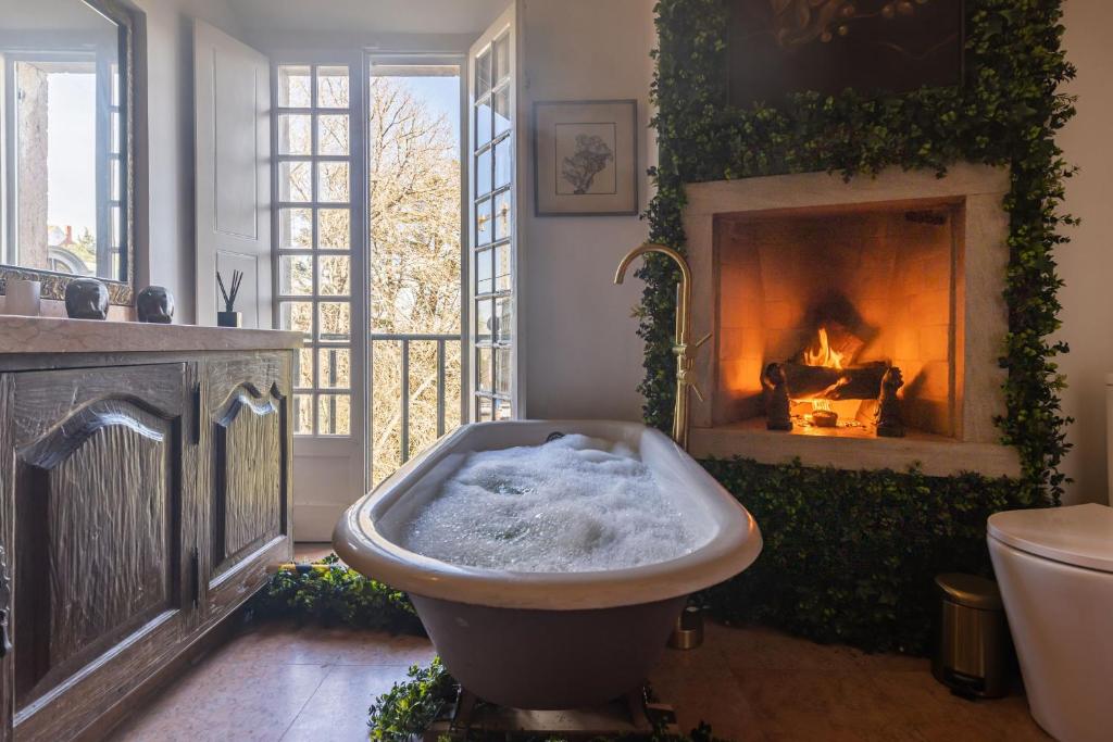 辛特拉Sintra WOW - Unique double Smart Room in 17th century Palace! Hot tub, Snooker, BBQ, PS5, Sauna, Gym的带浴缸的浴室(位于壁炉前)