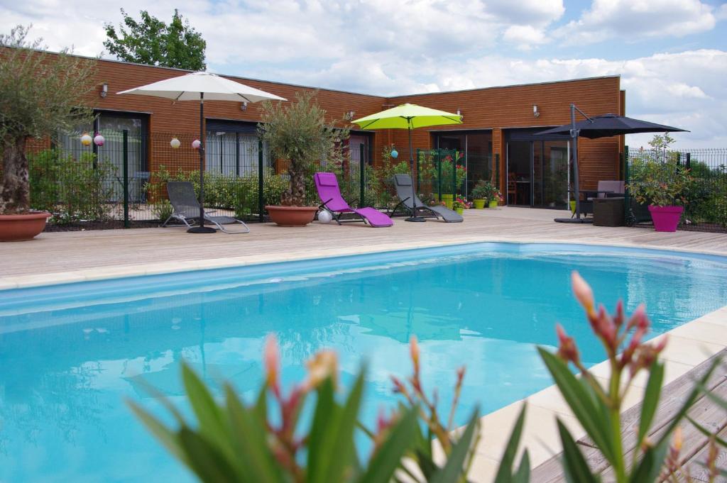 Mer莱斯奥布瑞斯杜查特旅馆的一座带椅子和遮阳伞的游泳池位于一座建筑旁边