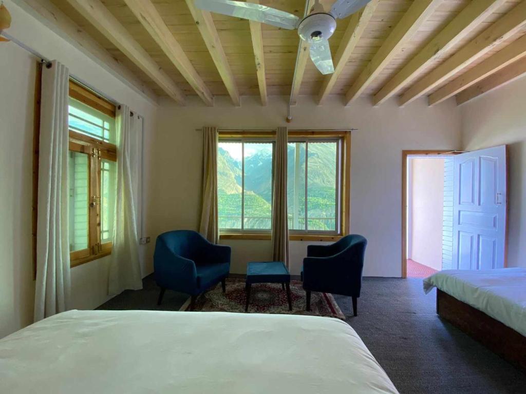罕萨Hunza Lounge的一间卧室配有两把椅子和一张床,设有窗户。