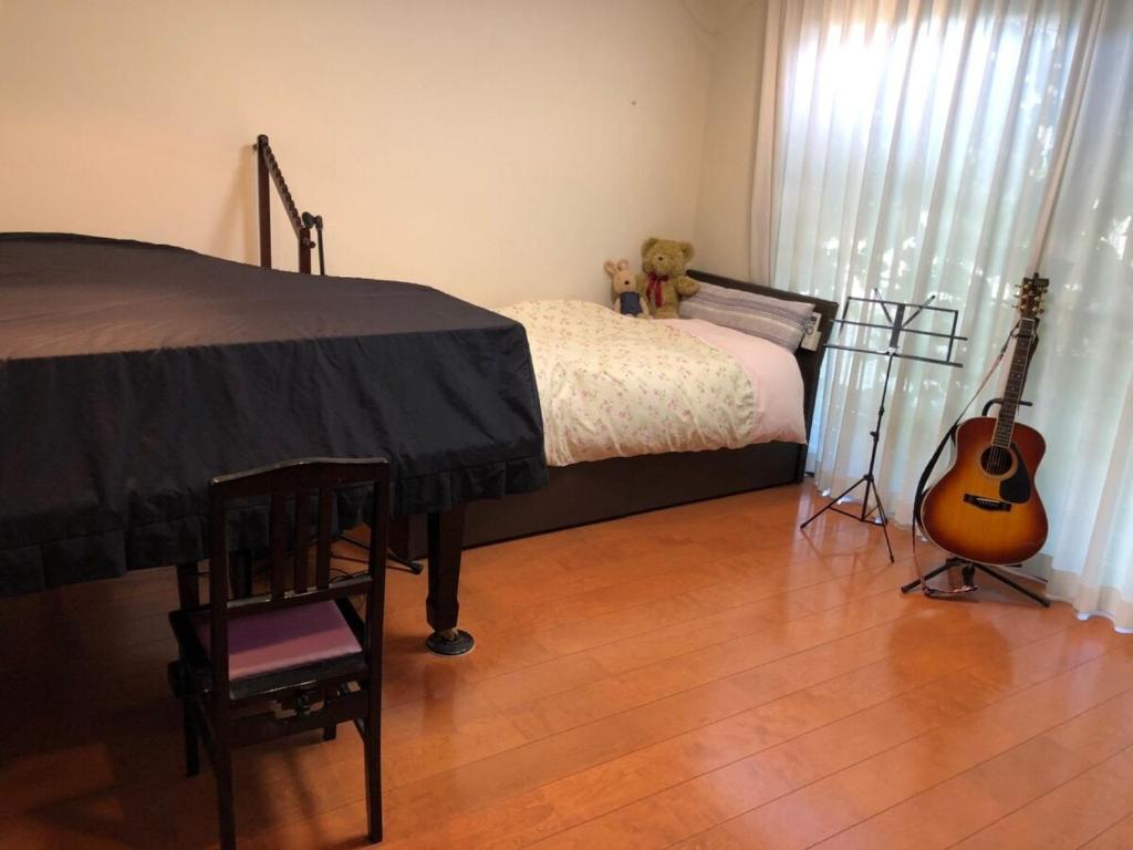 熊本KOTO TEA HOUSE - Vacation STAY 12837的一间卧室配有一张带吉他和椅子的床