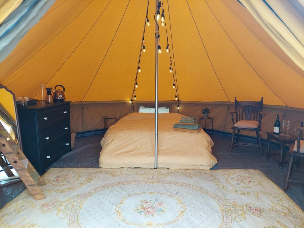 GingelomGlamping Hoeve Thenaers的帐篷内的卧室,配有一张床和一张桌子