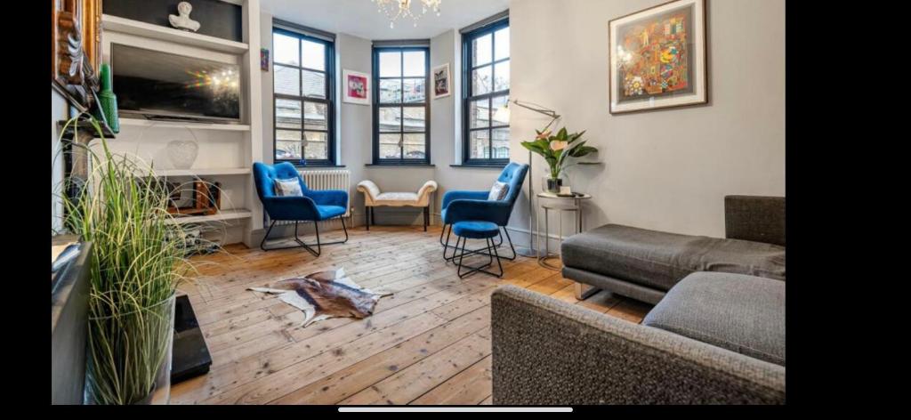 伦敦Tower Bridge Shad Thames, 3beds ,Aircon, Balcony View of Shard, Luxury & Boutique with Van Parking upto 4 Vans cars Ideal for Builders ShopFitters secure cctv 3Bedrooms的客厅配有沙发、椅子和电视