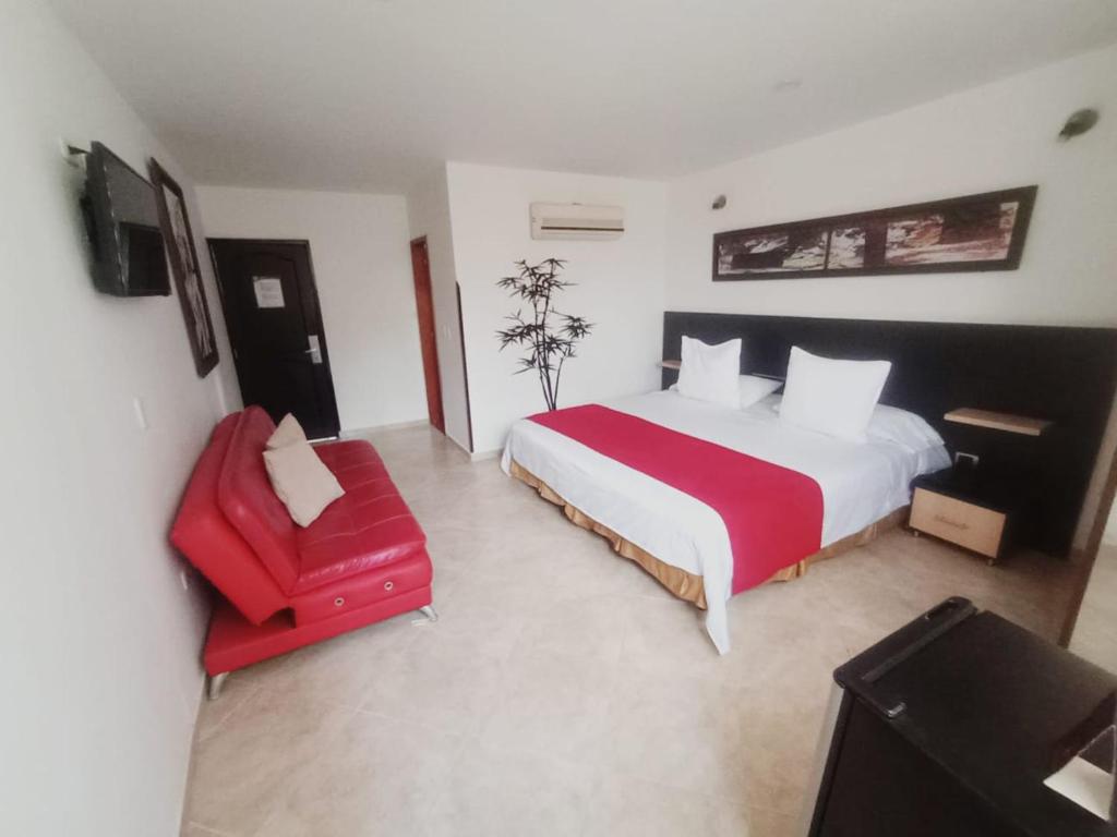 布卡拉曼加阿莱西奥酒店的一间卧室配有一张大床和一张红色椅子