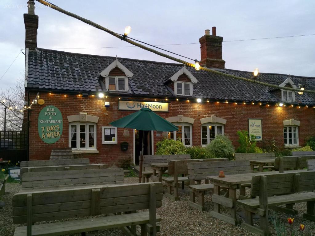 Pulham Saint Mary the VirginThe Half Moon Inn Rushall IP21 4QD的砖砌建筑前的木凳餐厅