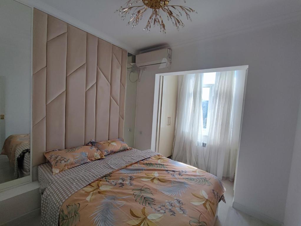 塔什干Светло и Уютно в центре города !的一间卧室配有一张带木制床头板的床和窗户。