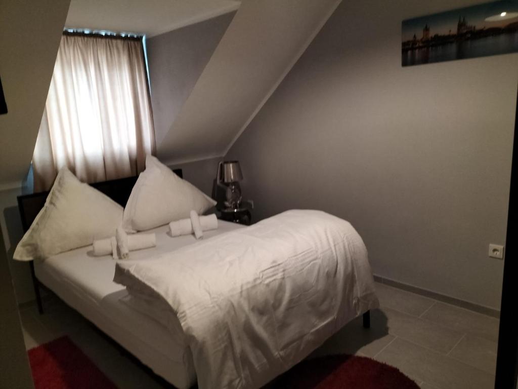 科隆Niehler Hotel的一间卧室配有一张带白色床单的床和一扇窗户。