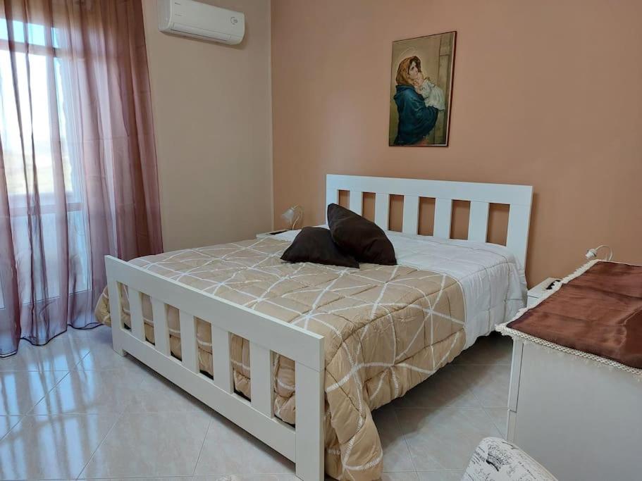 GiardinelloAppartamento in Villa Lory的卧室配有白色的床和墙上的绘画作品