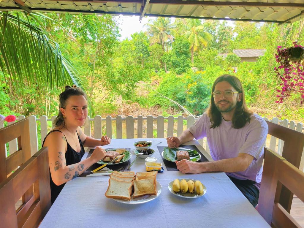 蒂瑟默哈拉默JAMI River Side Hotel & Yala Safari Place的坐在餐桌旁吃饭的男人和女人