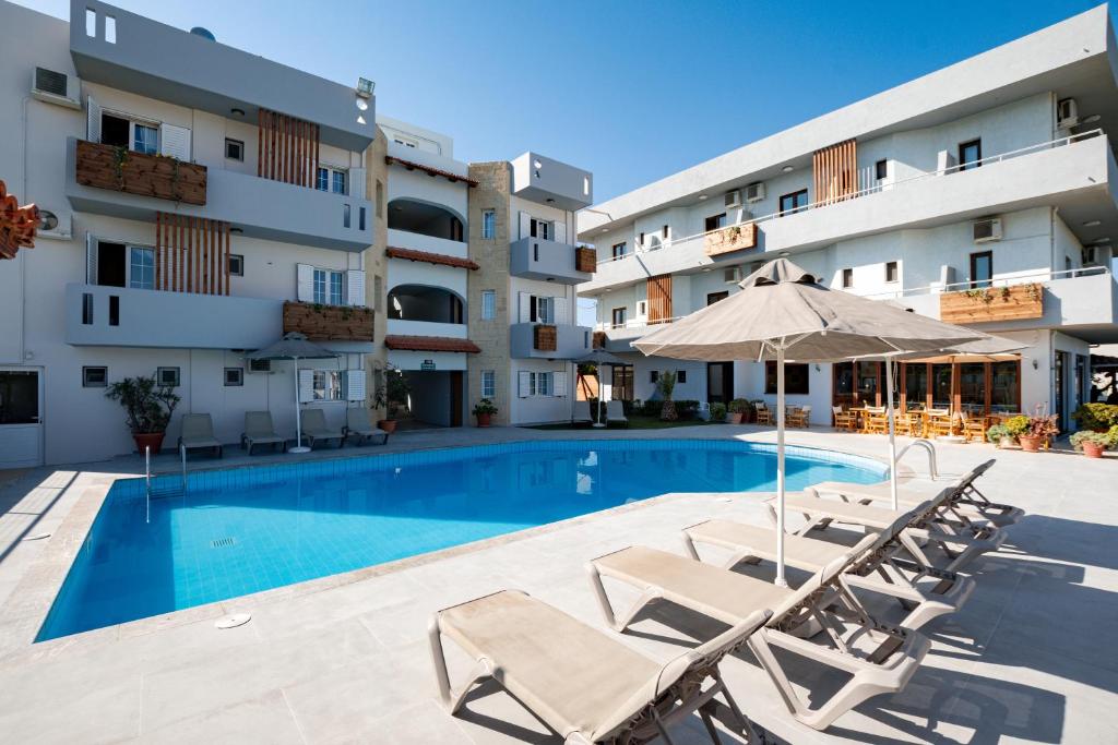 库基尼坎尼奥Dimitra Hotel & Apartments by Omilos Hotels的一座带椅子和遮阳伞的游泳池位于大楼旁