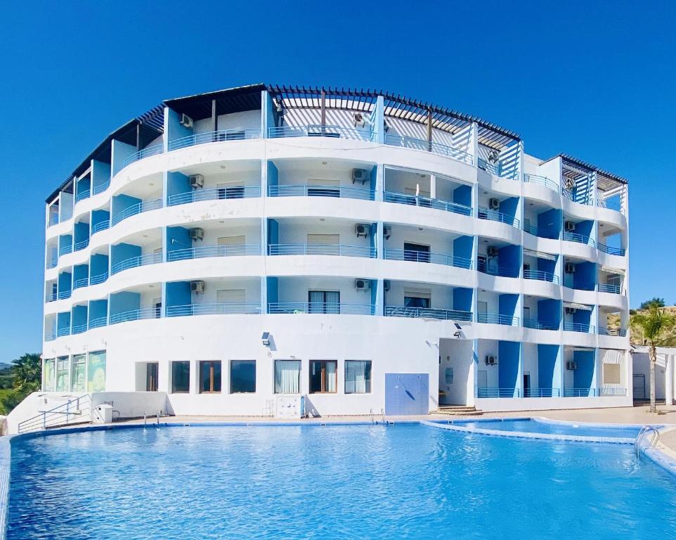 卡博尼格洛Cabo Dream Apparthotel的一座白色的大建筑,前面设有一个游泳池