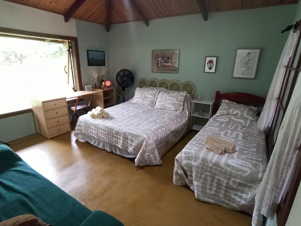 卡瓦坎特Chalés Pássaros do Cerrado的一间卧室设有两张床、一张桌子和一个窗口。