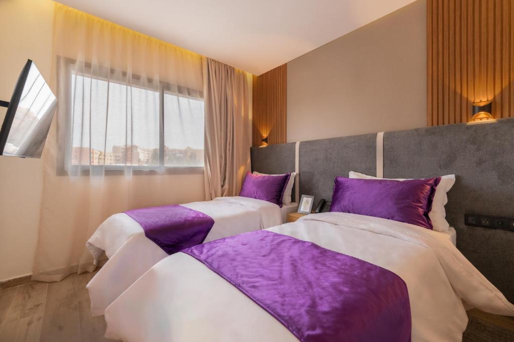 马拉喀什Appart Hôtel Rambla的紫色枕头间内的两张床