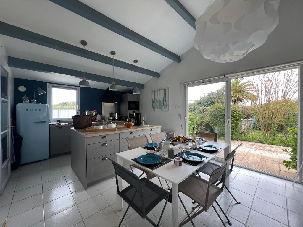 圣马丹德雷Villa de la Cible的一间带白色桌椅的厨房和一间带蓝色墙壁的厨房