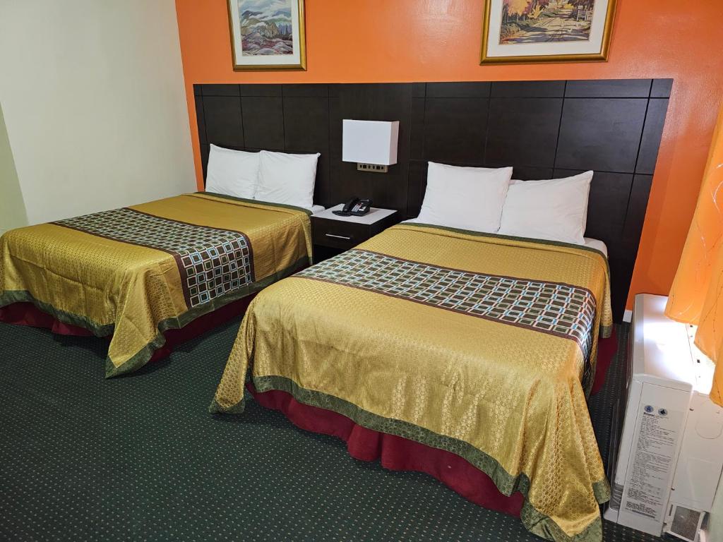 Coniston诺维克汽车旅馆的橙色墙壁的酒店客房内的两张床