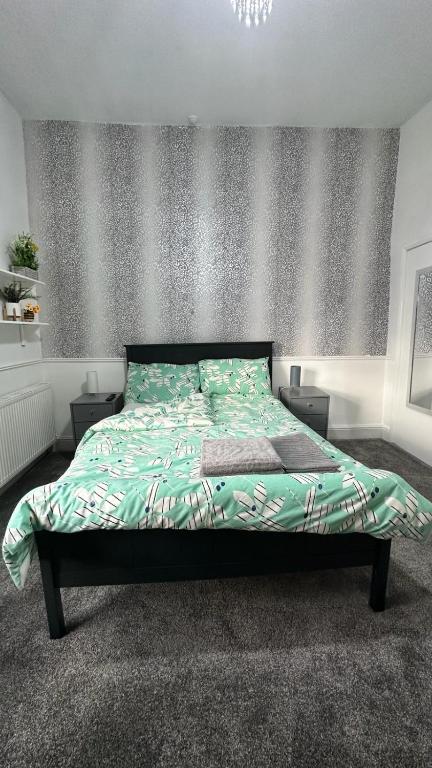 曼彻斯特Ur Place 204的卧室内的一张带绿色棉被的床