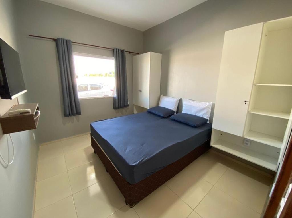 圣阿马鲁Dunas residence casa 03的一间卧室配有一张带蓝色床单的床和一扇窗户。