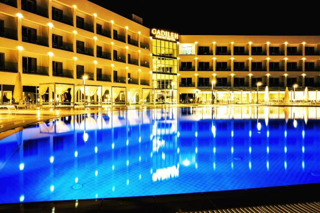 吉布提Gadileh Resort Hotel的一座大型建筑,在晚上设有大型游泳池