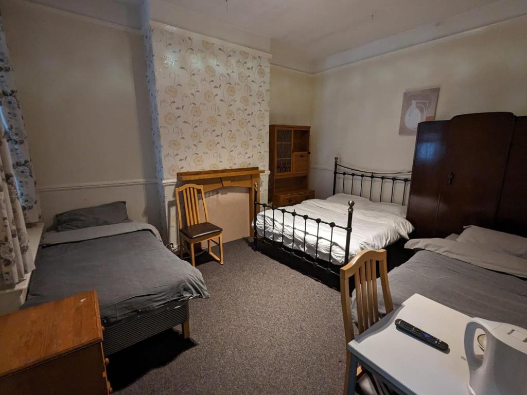 米德尔斯伯勒OYO Ormsby Townhouse的一间卧室配有两张床、一张桌子和一张桌子