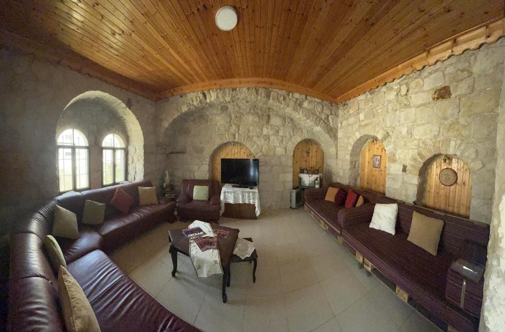 卡拉克Al Karak House的客厅设有真皮沙发和石墙