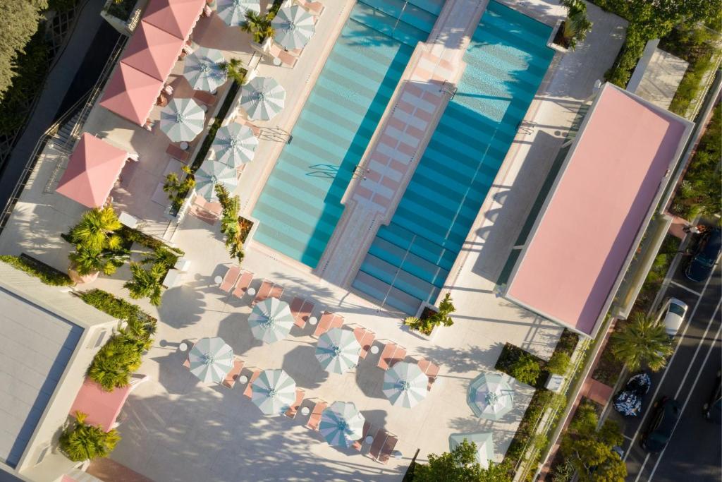 迈阿密海滩The Goodtime Hotel, Miami Beach a Tribute Portfolio Hotel的享有带椅子和遮阳伞的游泳池的上方景色