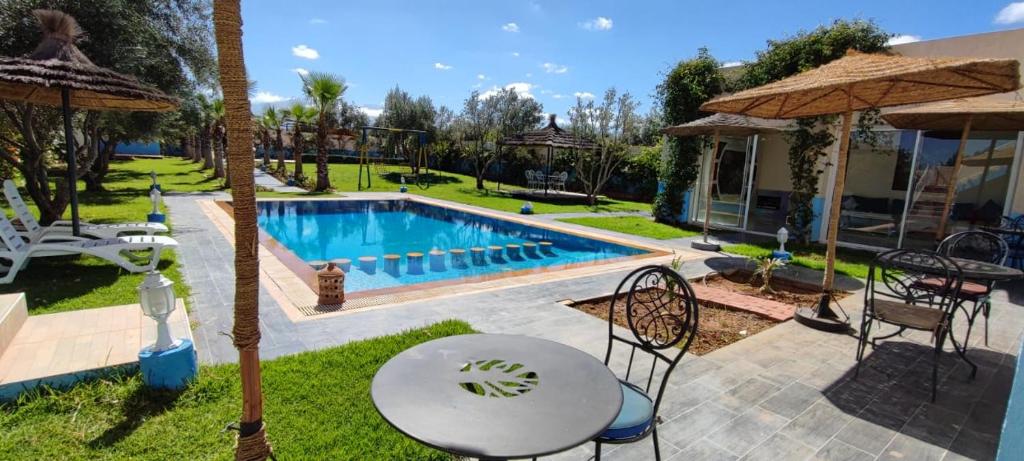 马拉喀什Hotel Jnane riad的后院设有游泳池、桌子和椅子