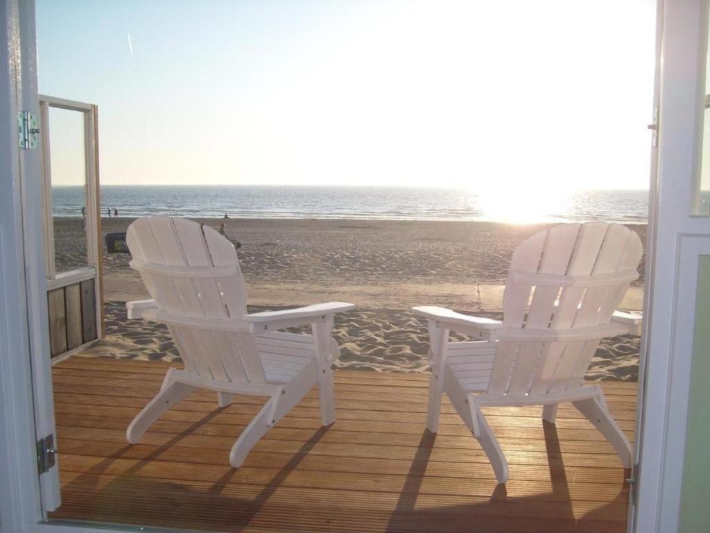 滨海韦克Strandhaus direkt am Meer的两把白色椅子坐在一个俯瞰着海滩的门廊上