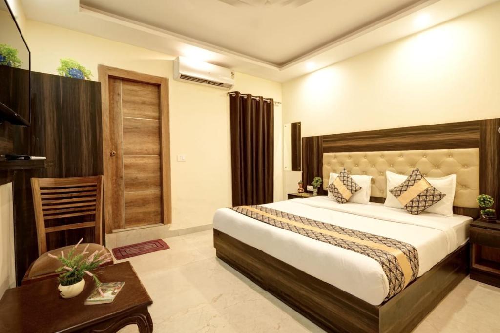 新德里Hotel IVY Near IGI Delhi Airport的酒店客房配有一张床铺和一张桌子。