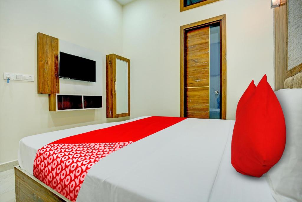 齐拉克普尔Super OYO Flagship Hotel Elista的卧室的床上有一个红色枕头